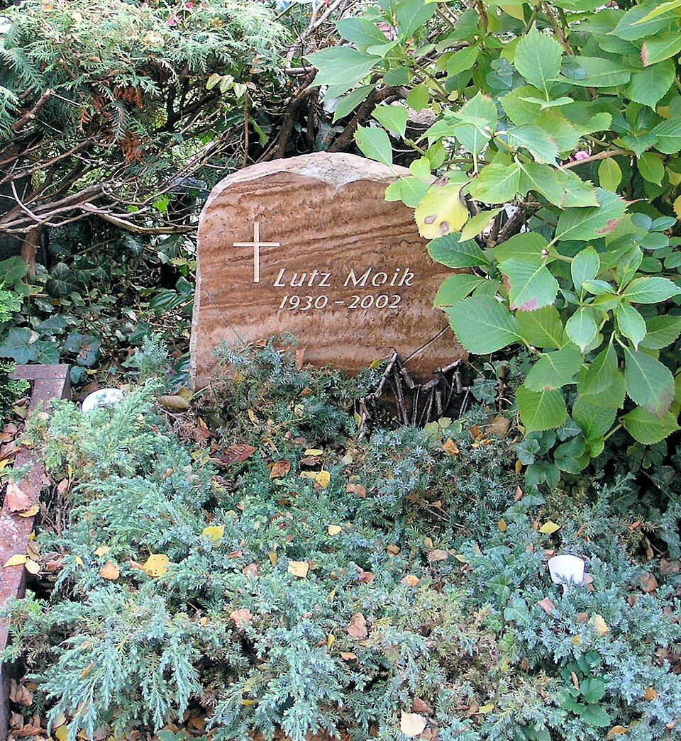 Lutz Moik’s gravestone among dense planting at Stubenrauchstraße Cemetery